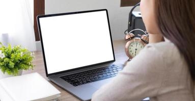 Mockup image of a woman using and typing on laptop with blank white desktop screen on wooden table photo