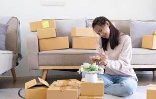 Young attractive asian woman owner startup business look at camera work happy with box at home prepare parcel delivery in sme supply chain photo