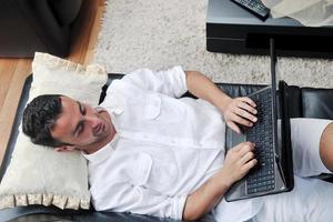 Portrait of a relaxed young guy using laptop at home photo