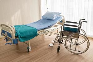 cama de hospital y silla de ruedas en la habitación del hospital foto