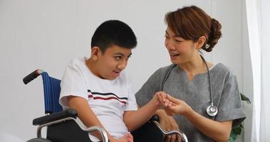 A physical therapist is talking to a disabled boy in a wheelchair. photo
