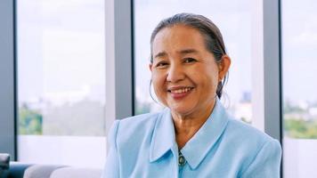 Portrait of smiling senior woman sitting on sofa at home. photo