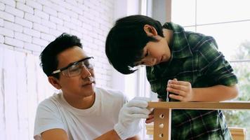 Young male carpenter teaching his son how to work with wood in workshop. photo