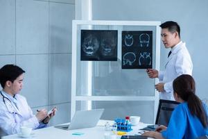 médico y asistentes médicos discutiendo sobre el resultado del diagnóstico en la película de rayos x. foto