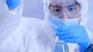 Scientist in PPE suite doing some research checking a liquid in a test tube at laboratory. photo