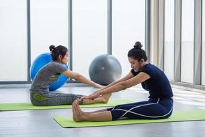 Two asian women doing yoga together at a gym. photo