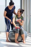 dos mujeres asiáticas haciendo yoga juntas en un gimnasio. foto