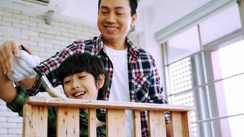 Young male carpenter teaching his son how to work with wood in workshop. photo