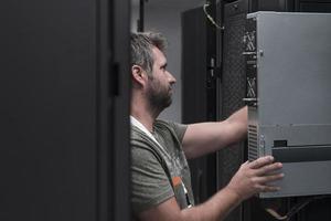 el ingeniero que trabaja en la sala de servidores o en el centro de datos, el técnico coloca en un rack un nuevo servidor de supercomputadora de mainframe de negocios corporativos o granja de minería de criptomonedas. foto