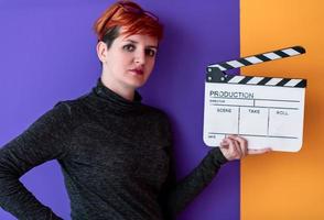 Mujer que sostiene la chapaleta de la película contra el fondo colorido foto