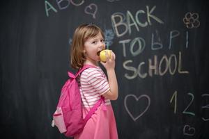 niño feliz con manzana y dibujo de regreso a la escuela en segundo plano foto