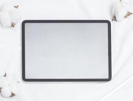 Tablet empty white screen with pencil and cotton flower on white background mockup for design photo