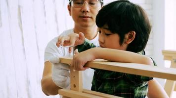 Young male carpenter teaching his son how to work with wood in workshop. photo