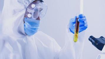 Scientist in PPE suite doing some research checking a liquid in a test tube at laboratory. photo