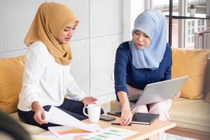 Two young muslim businesswomen discussing a work in the office. photo