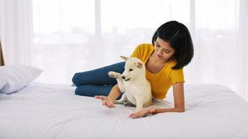 Happy woman and shiba inu dog lying together on a bed at home photo