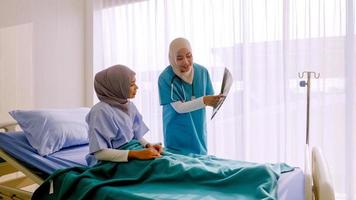 Muslim female doctor analysing disease to patient at hospital room. photo