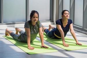 dos mujeres asiáticas haciendo yoga juntas en un gimnasio. foto