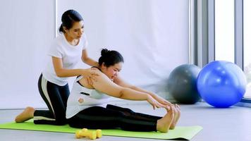 Young shapely woman helping chubby woman doing exercise in finess room. photo