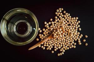 soybean in a spoon and bowl with oil on black background, top view, flat lay, top-down, selective focus.copy space. photo