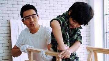 Young male carpenter teaching his son how to work with wood in workshop. photo