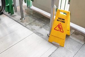 Yellow Caution slippery wet floor sign on the wet ground photo