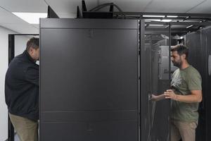 Technicians team updating hardware inspecting system performance in super computer server room or cryptocurrency mining farm. photo