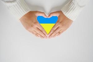salve a ucrania no más guerra en el concepto de mano de mujer y la bandera en forma de corazón. el patriotismo y proteger al pueblo de ucrania. foto