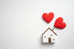 Small wooden house with hearts. Concept of protection or saving for buying new living area. Topic for loan and investment. photo