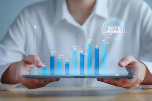 2023 goal and target. Hand holding tablet that showing a growing graph trader or virtual hologram stock. Set strategy and plan for future. Business management and financial concept. photo