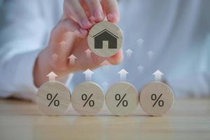 House and property investment and asset management concept. Interest rates, loan mortgage, house tax. Hand holding house icon on wooden circle from percent icon on wooden circle and rise of arrow. photo