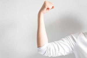 mujer caucásica puño mano y tensa el brazo para mostrar músculo sobre fondo blanco. foto