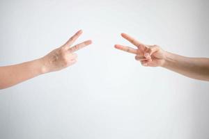 Two person playing rock paper scissors with both posturing scissors symbol on white background. photo