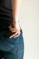 una mujer saca una billetera de dinero del bolsillo de los jeans sobre fondo blanco con espacio para copiar. foto