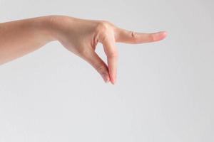 una mano de mujer que hace una postura con el pulgar y el índice se tocan juntos y el otro dedo se estira hacia adelante sobre fondo blanco. foto