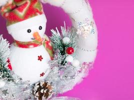 primer plano de muñeco de nieve en corona de navidad suave blanca con muchas decoraciones de baratija. foto