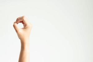 una mano formando un círculo, o mostrando el número cero usando el pulgar tocando otros dedos sobre fondo blanco. foto