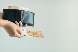 una mano recogiendo un billete de la cartera corta y pagando en euros. foto
