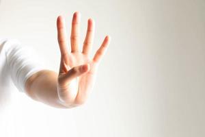 A hand showing number four in close-up on white background and little light. photo