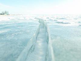 primer plano de la superficie de la grieta de hielo y el horizonte y el cielo azul detrás. foto