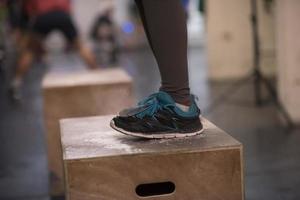 black woman is performing box jumps at gym photo