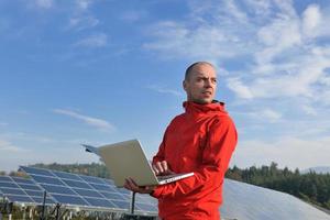 ingeniero que usa una computadora portátil en el campo de la planta de paneles solares foto