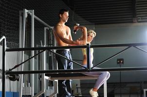 mujer en el gim de fitness trabajando con entrenador personal foto