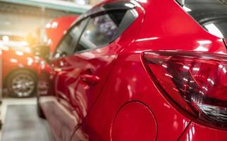 Rear view of red SUV car parked in car repair shop. Red car in workshop of service station. Vehicle inside garage workshop. Cleseup tailight. Red car in garage for repair and maintenance service. photo