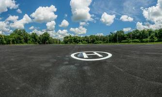 Asphalt helipad in the forest. Landscape of helipad. Helipad area against blue sky and white cumulus clouds in sunny day. Platform for helicopters and powered lift aircraft. Heliport of helicopter. photo