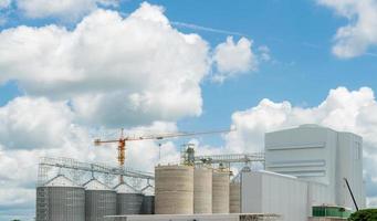 Animal feed factory construction site. Agricultural silo at feed mill factory. Tank for store grain in feed manufacturing. Seed stock tower for commercial animal feed production. Animal food industry. photo