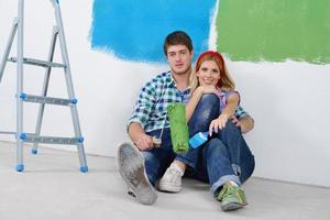 pareja joven feliz relajándose después de pintar en un nuevo hogar foto