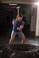 man workout with hammer and tractor tire photo