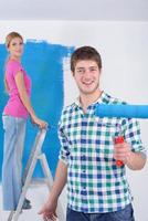 pareja feliz pintando una pared en su nuevo hogar foto