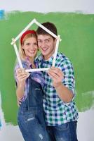 pareja feliz pintando una pared en su nuevo hogar foto